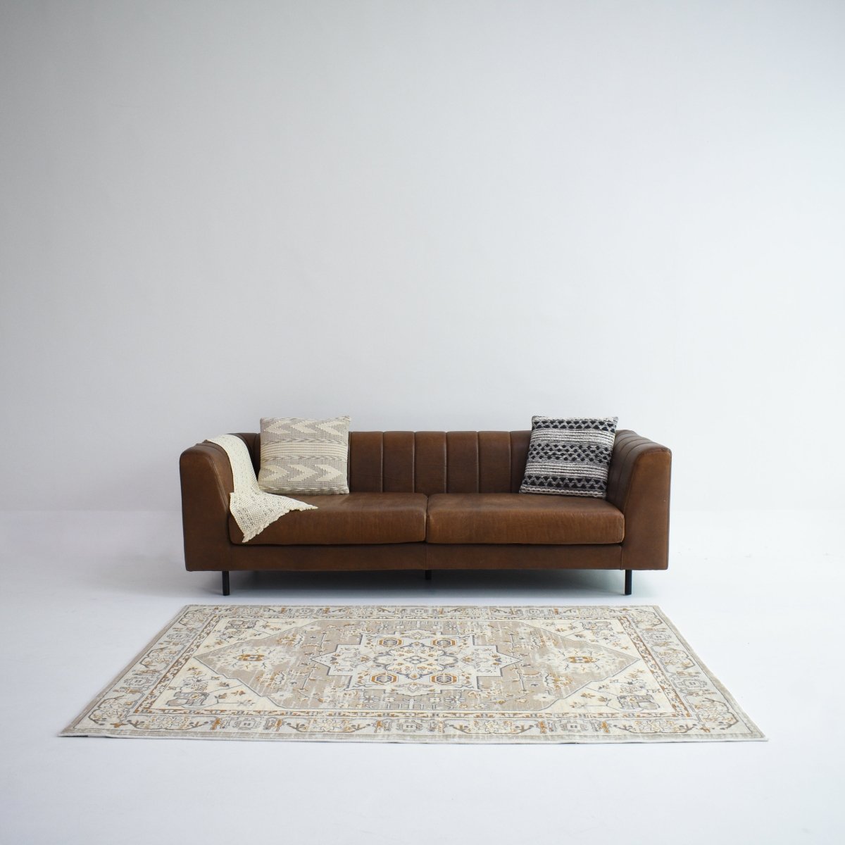 A Persian-style rug with beige and gold in front of a sofa. The patterns add a touch of elegance to the living room.