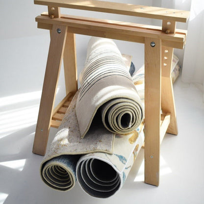 A collection of rolled-up carpets displaying different designs, including stripes and floral patterns, stored on a rack.