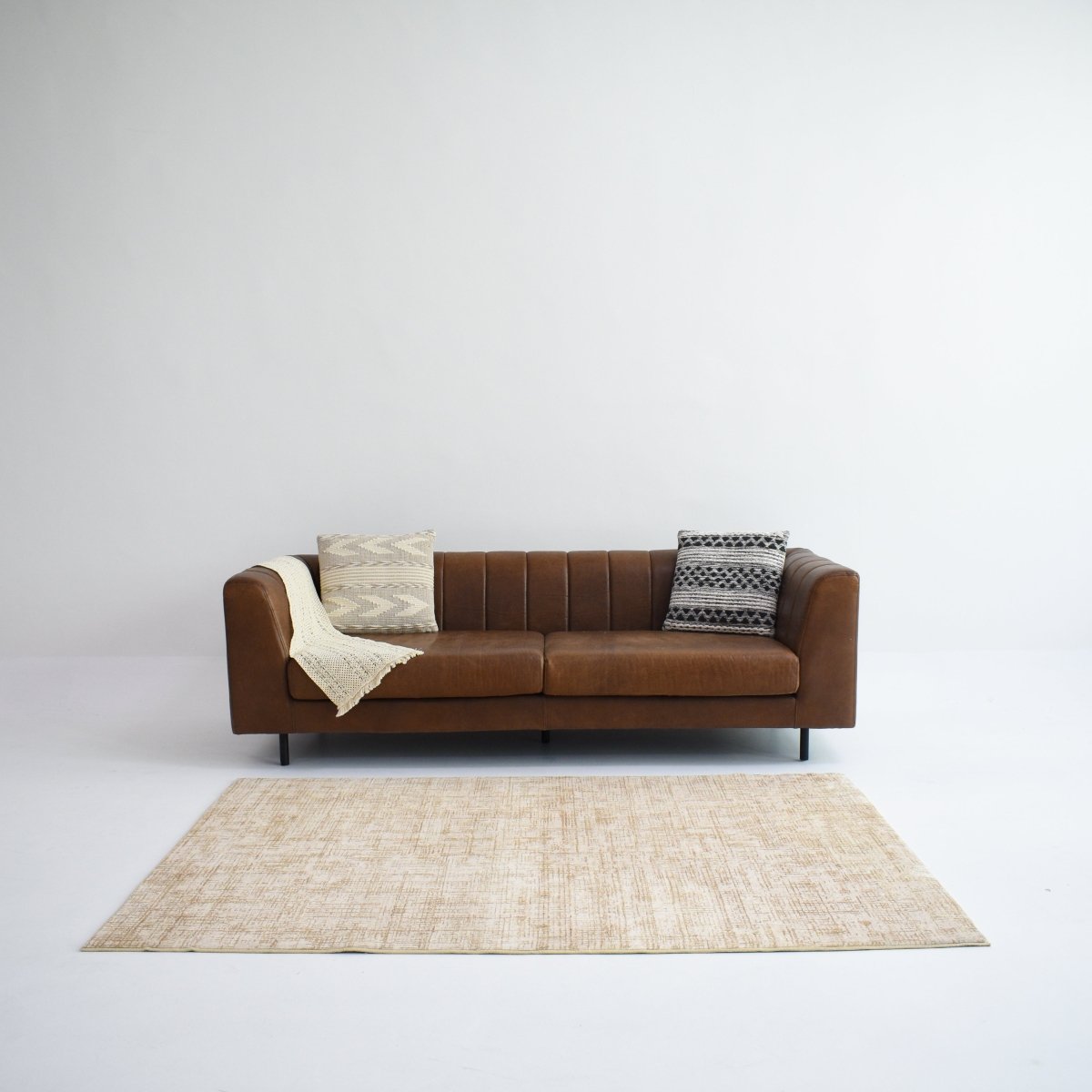 A beige crosshatch carpet placed in a living room, paired with a brown sofa creating a warm and contemporary atmosphere.