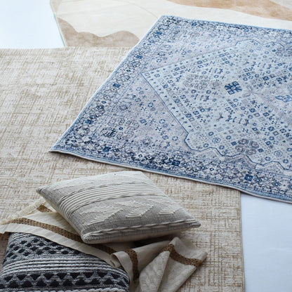 A display of layered carpets featuring a beige textured design and a detailed blue and white patterned rug.