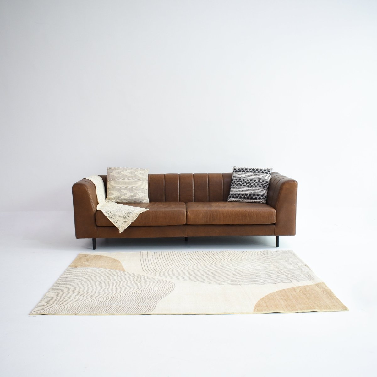 A rug with abstract flowing shapes in soft beige and warm brown tones, creating a gentle contrast of linear textures.