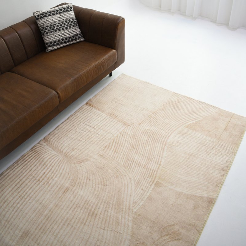 A rug with soft, flowing curved lines and subtle tonal variations in beige, adding texture to a minimalist setting.